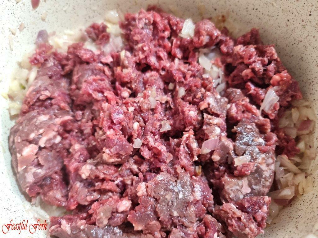 Adding ground beef with sauteed garlic and onions