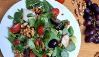 Salad with grapes and walnuts on a plate surrounded by ingredients