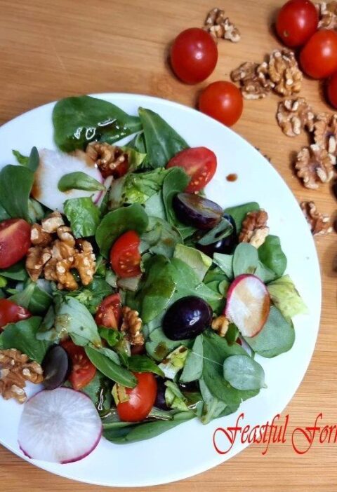 Salad with grapes and walnuts on a plate surrounded by ingredients