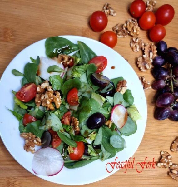 Salad with grapes and walnuts on a plate surrounded by ingredients