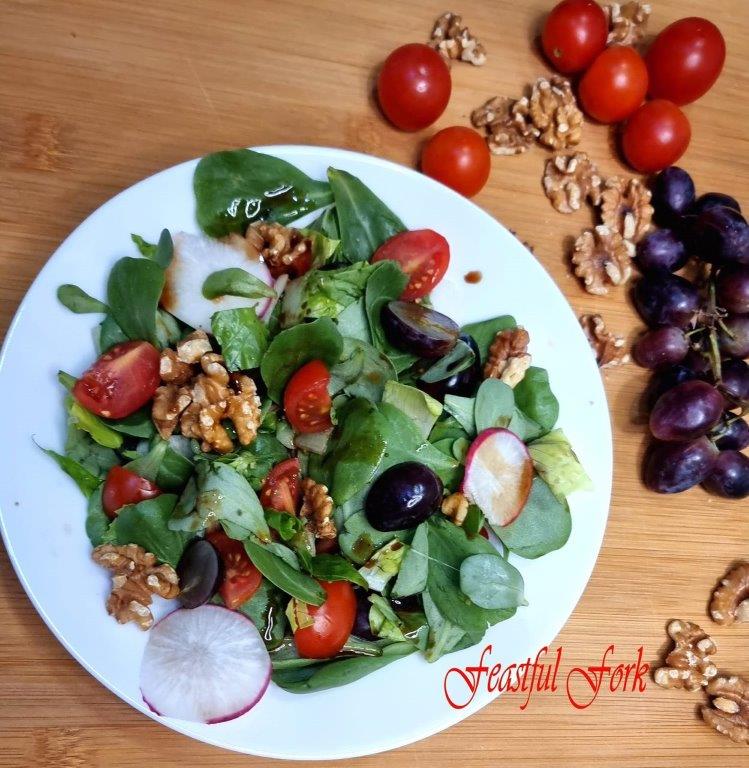 Salad with grapes and walnuts on a plate surrounded by ingredients